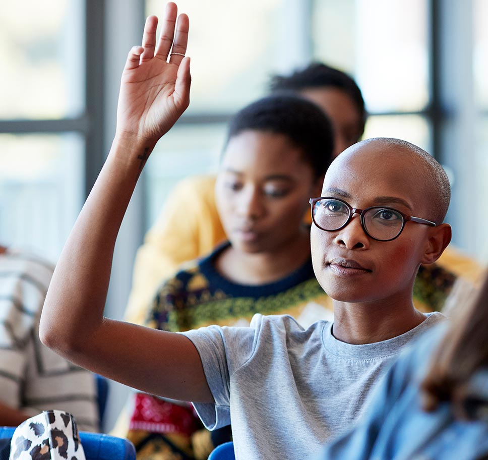 A student raises their hand in glass while other students look on.