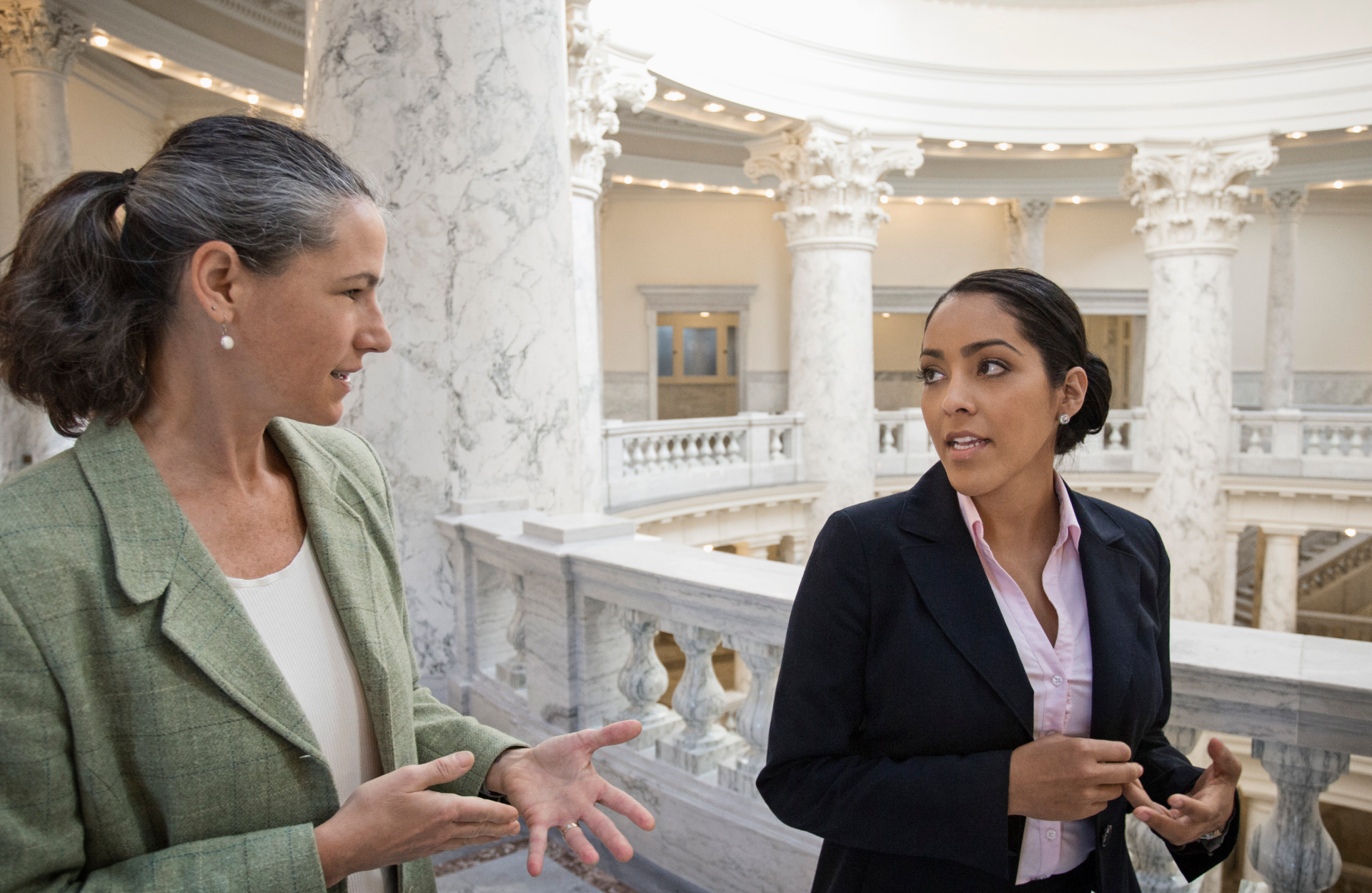 Two women walking and talking in a government building. 