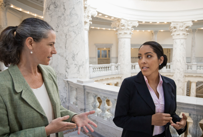 Two women walking and talking in a government building. 